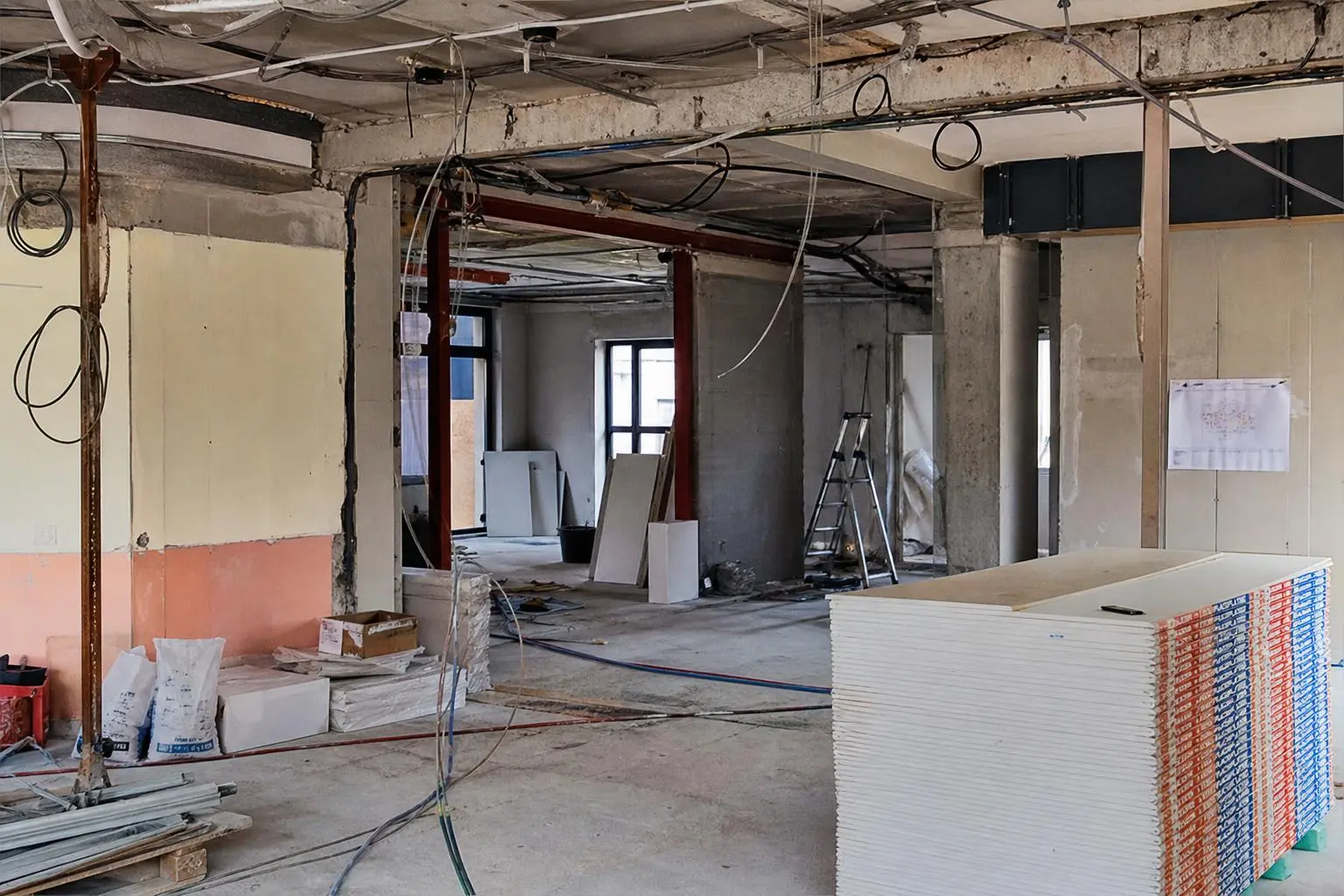 Chantier de rénovation bâtiment, espaces en construction avec plaques de plâtre, câbles et échelles, ambiance atelier. Formation btp reconversion mentionnée.